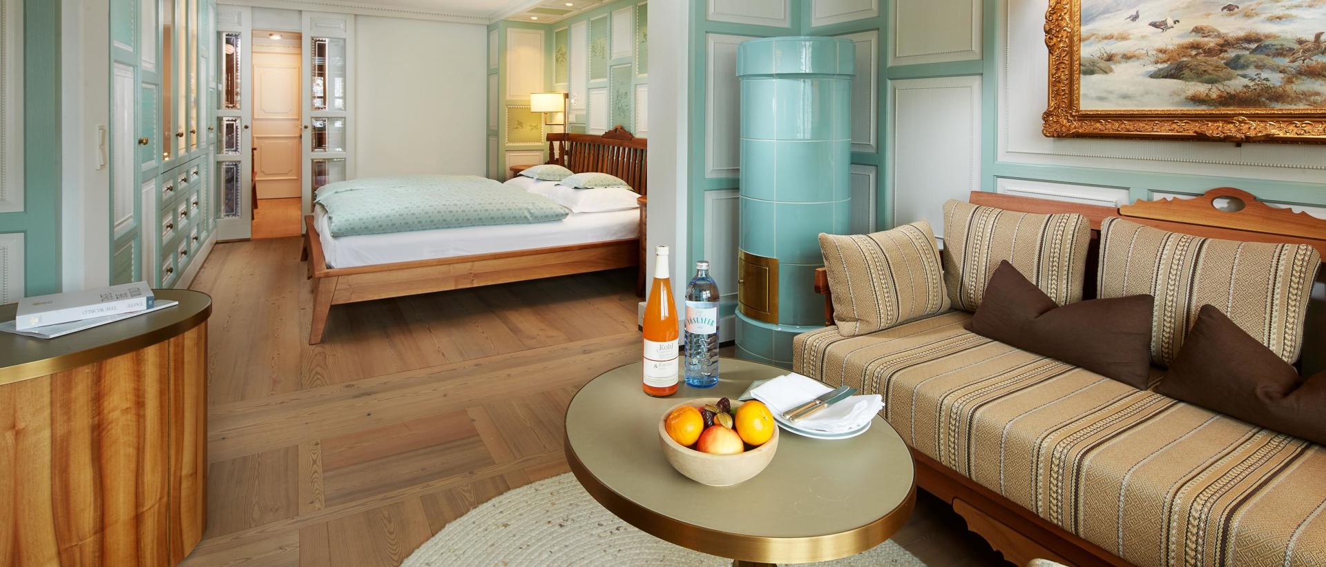 Hotel Post Lech Zimmer mit Bett, Sofa, Tisch und Gemälde