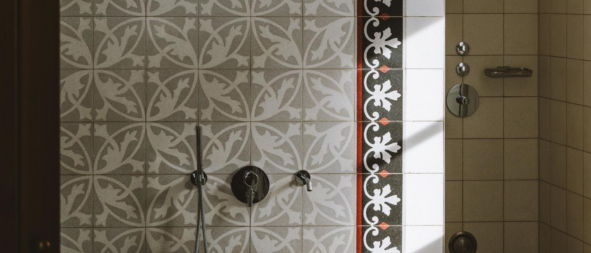 Freistehende Badewanne mit dekorativen Fliesen im Hotel Post Lech