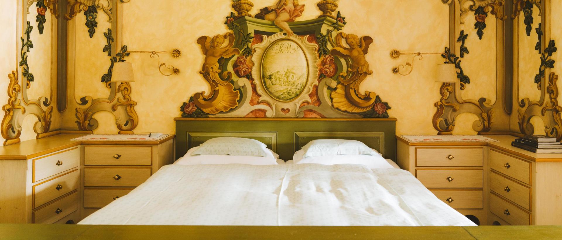 Hotel Post Lech mit Doppelbett und kunstvoll verziertem historischem Schlafzimmer