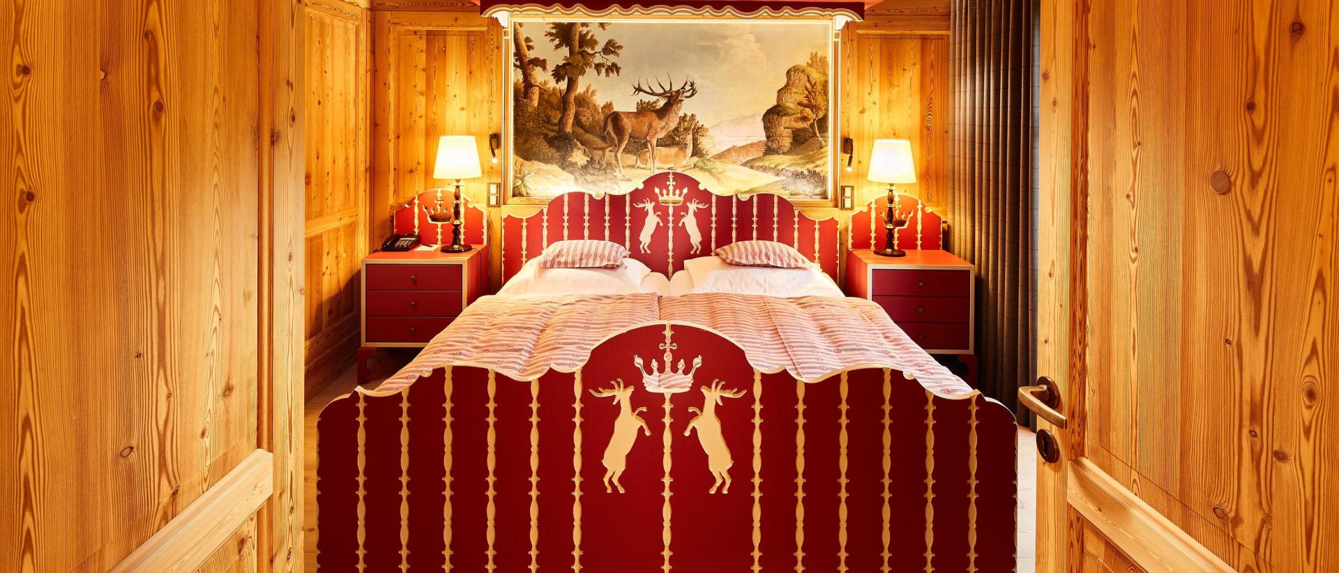 Hotel Post Lech: Rustikales Doppelbettzimmer mit rotem Bett und Holzvertäfelung