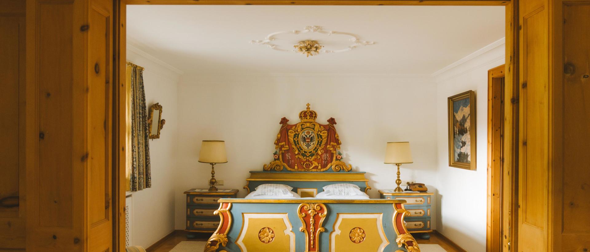 Hotel Post Lech mit elegantem Schlafzimmer und kunstvoll verziertem Bett