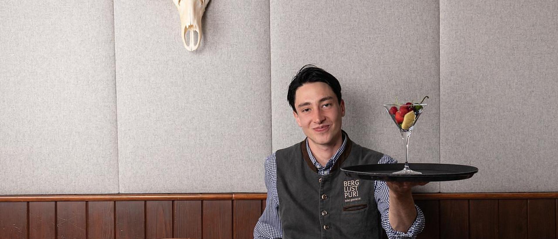 Hotel Gassner **** Superior: Staff member with tray beneath antlers on the wall