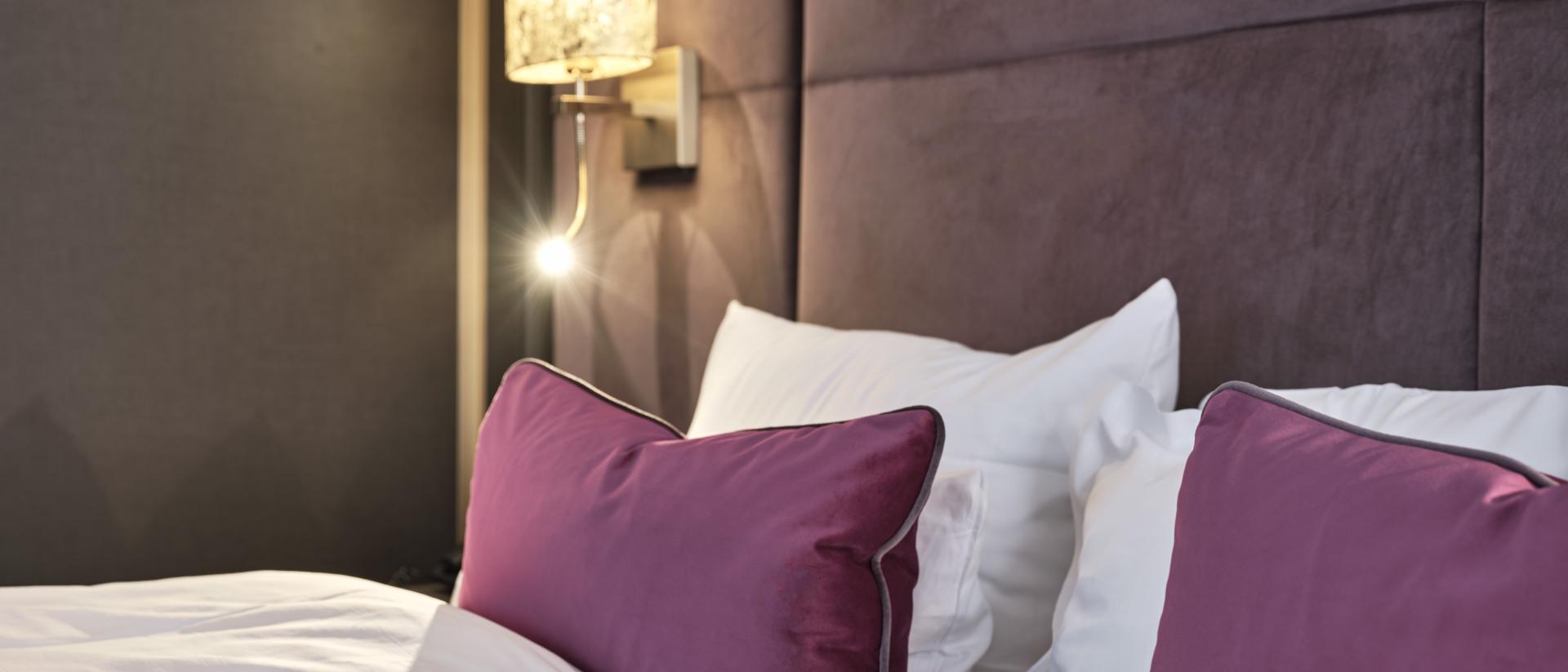 Bett mit weißen und violetten Kissen im Hotel Reppert