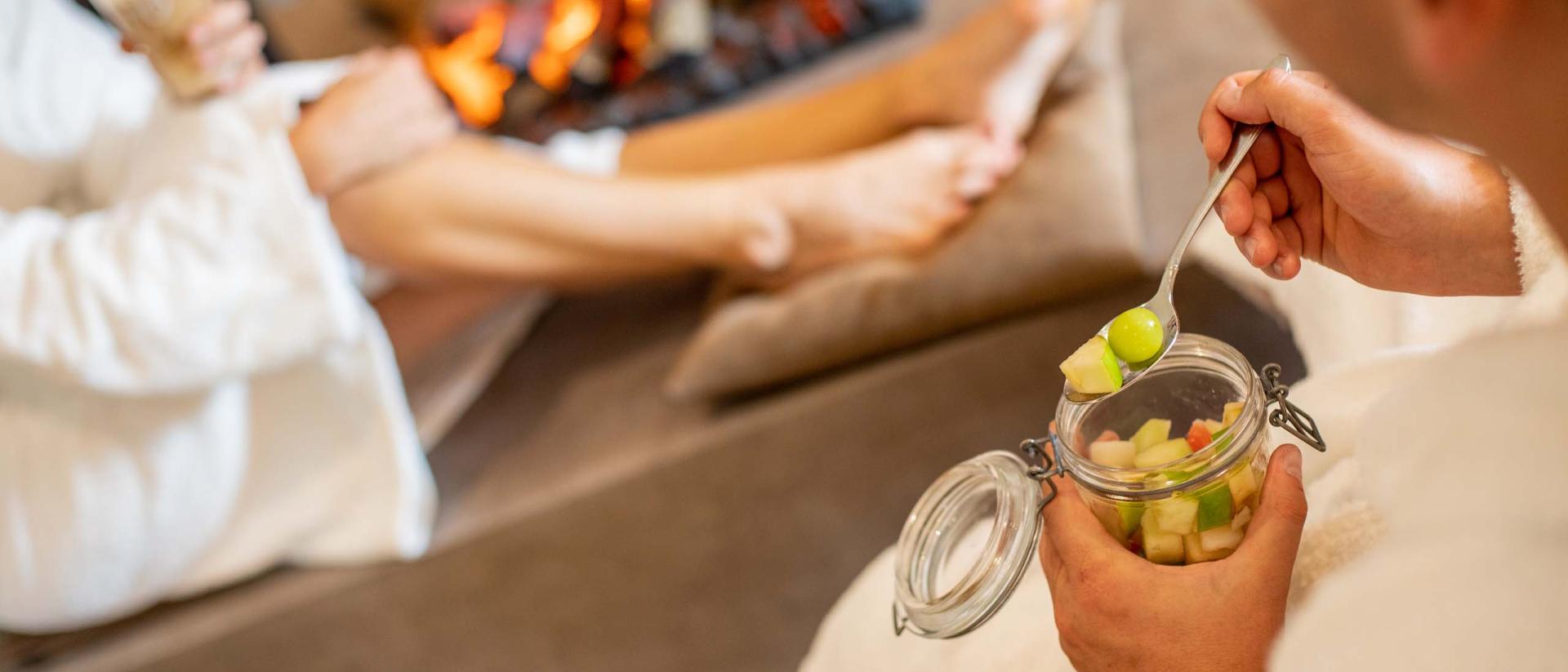 Entspannte Gäste im Bademantel beim Essen vor dem Kamin im Pfalzblick Wald Spa Resort