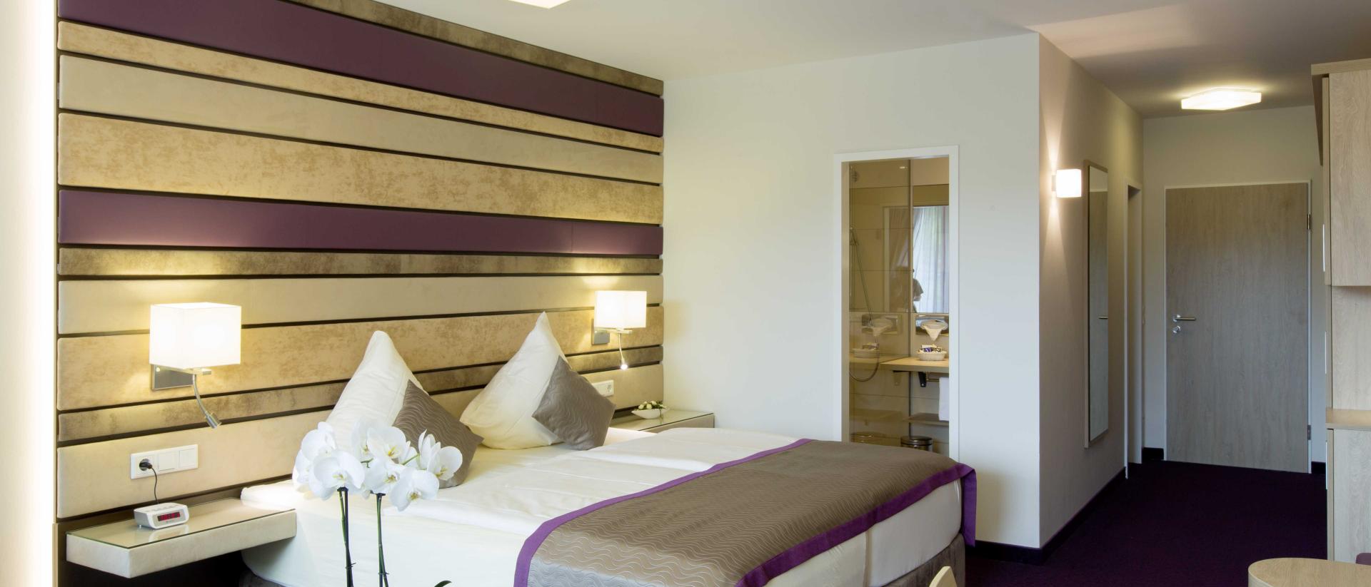 Modernes Hotelzimmer im Pfalzblick Wald Spa Resort mit Doppelbett und lila Akzenten
