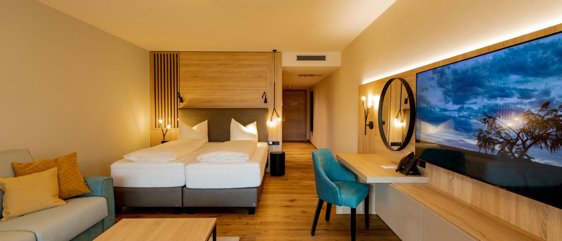 Modernes Zimmer im Pfalzblick Wald Spa Resort mit Doppelbett und Sitzbereich