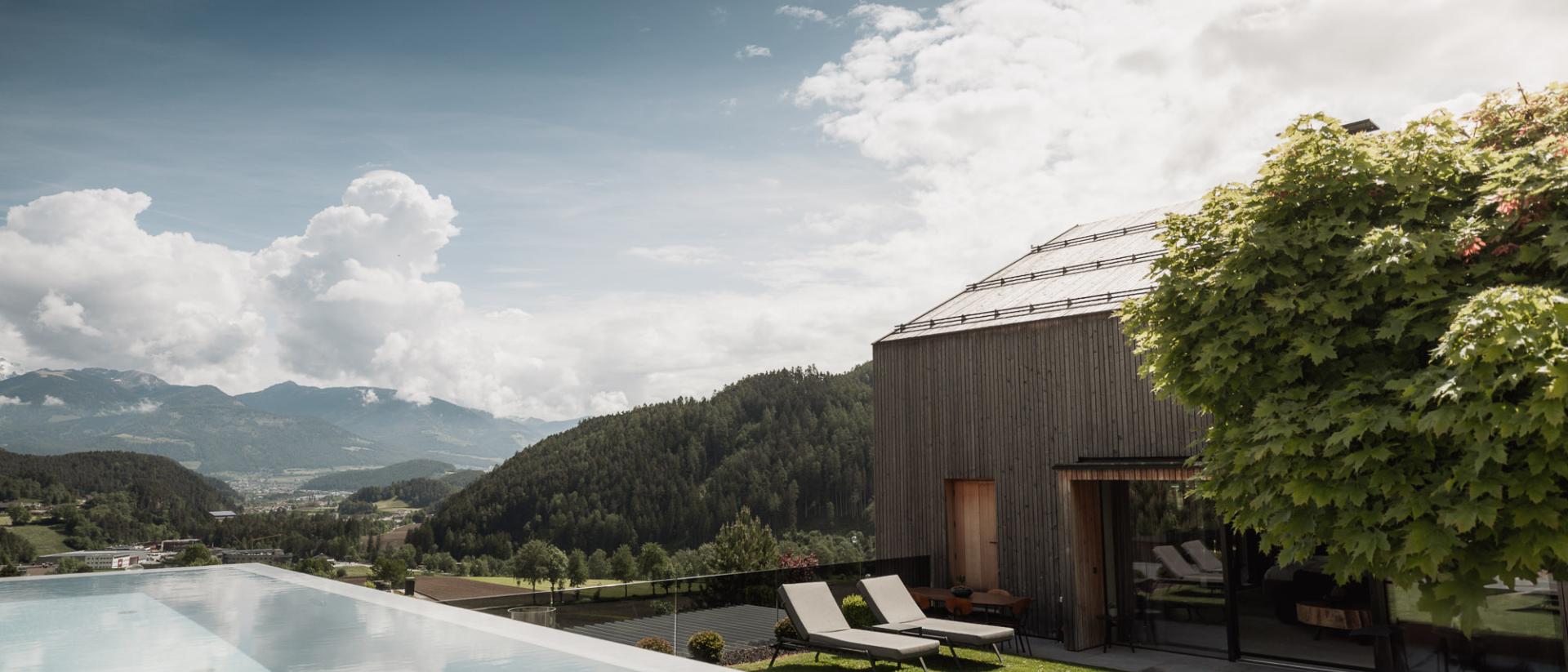Chalet Purmontes con piscina a sfioro e vista sulle montagne sotto un cielo nuvoloso