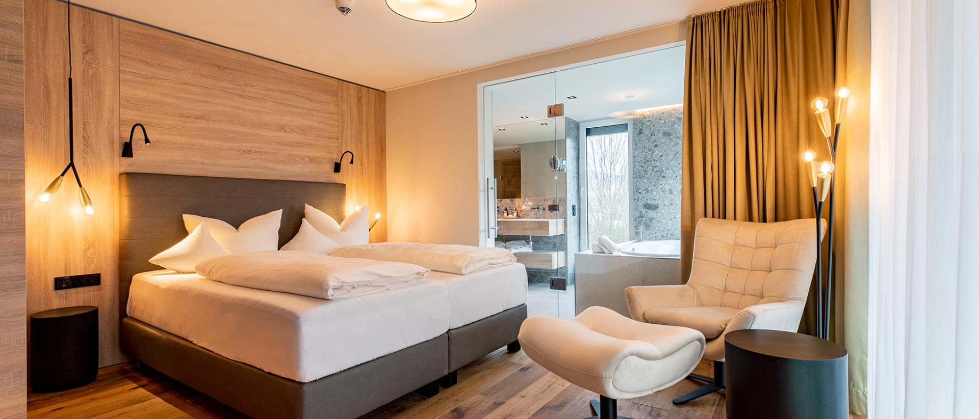 Modernes Schlafzimmer im Pfalzblick Wald Spa Resort mit Holzfußboden und gemütlichem Sessel