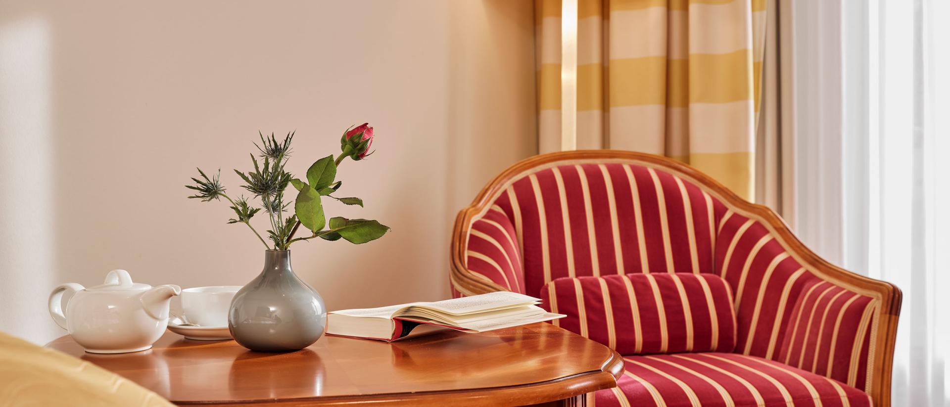 Gemütliche Sitzecke mit gestreiftem Sessel und Tisch im Hotel Reppert