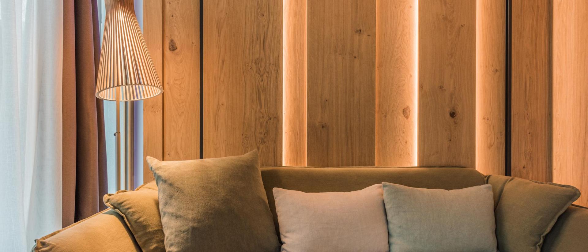 Modernes Sofa im Hotel Winkler mit warmem Holzpaneel und Stehlampe