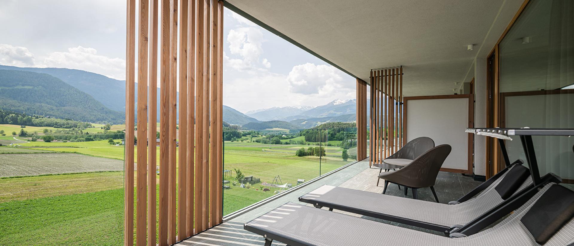 Balkon mit Liegestühlen im Hotel Winkler mit Blick auf grüne Felder und Berge