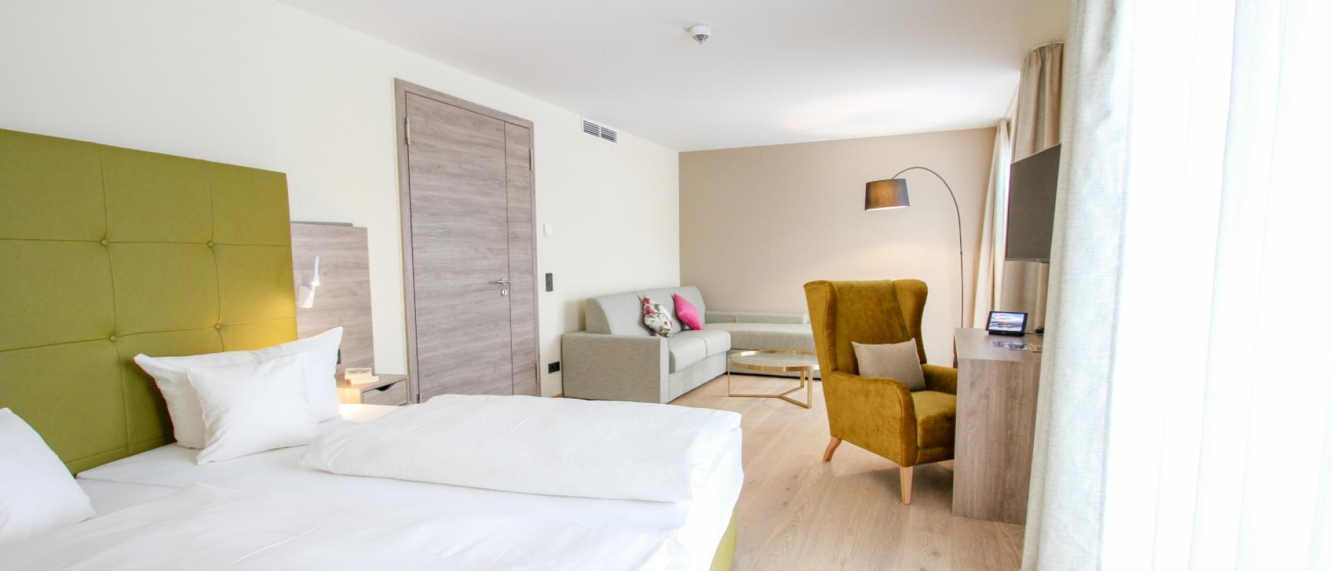 Helles Hotelzimmer im Pfalzblick Wald Spa Resort mit Doppelbett und Sitzbereich