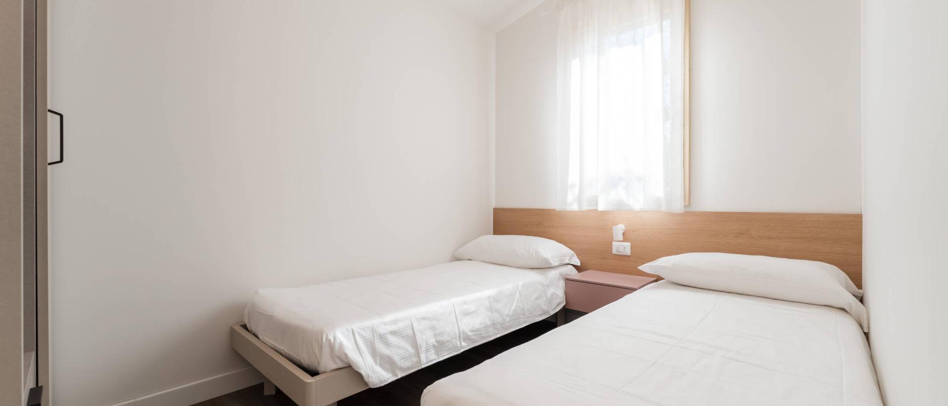 Schlichtes Doppelzimmer im Natural Village Resort mit zwei Einzelbetten und hellem Fenster