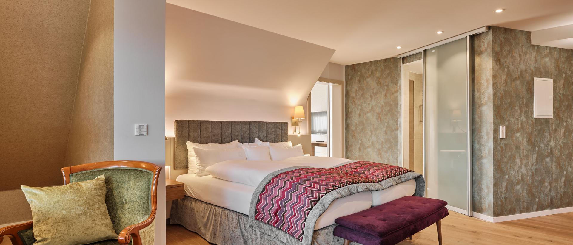 Modernes Schlafzimmer im Hotel Reppert mit Doppelbett und gemütlichem Sessel