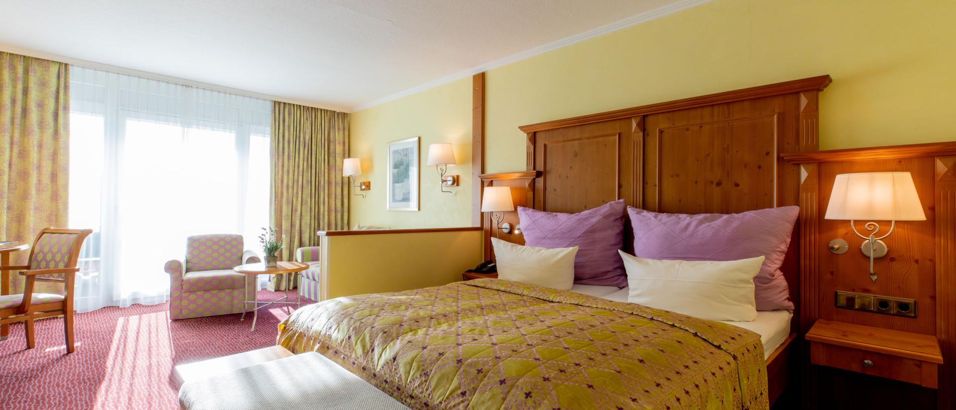 Komfortables Zimmer im Pfalzblick Wald Spa Resort mit großem Bett und Sitzbereich