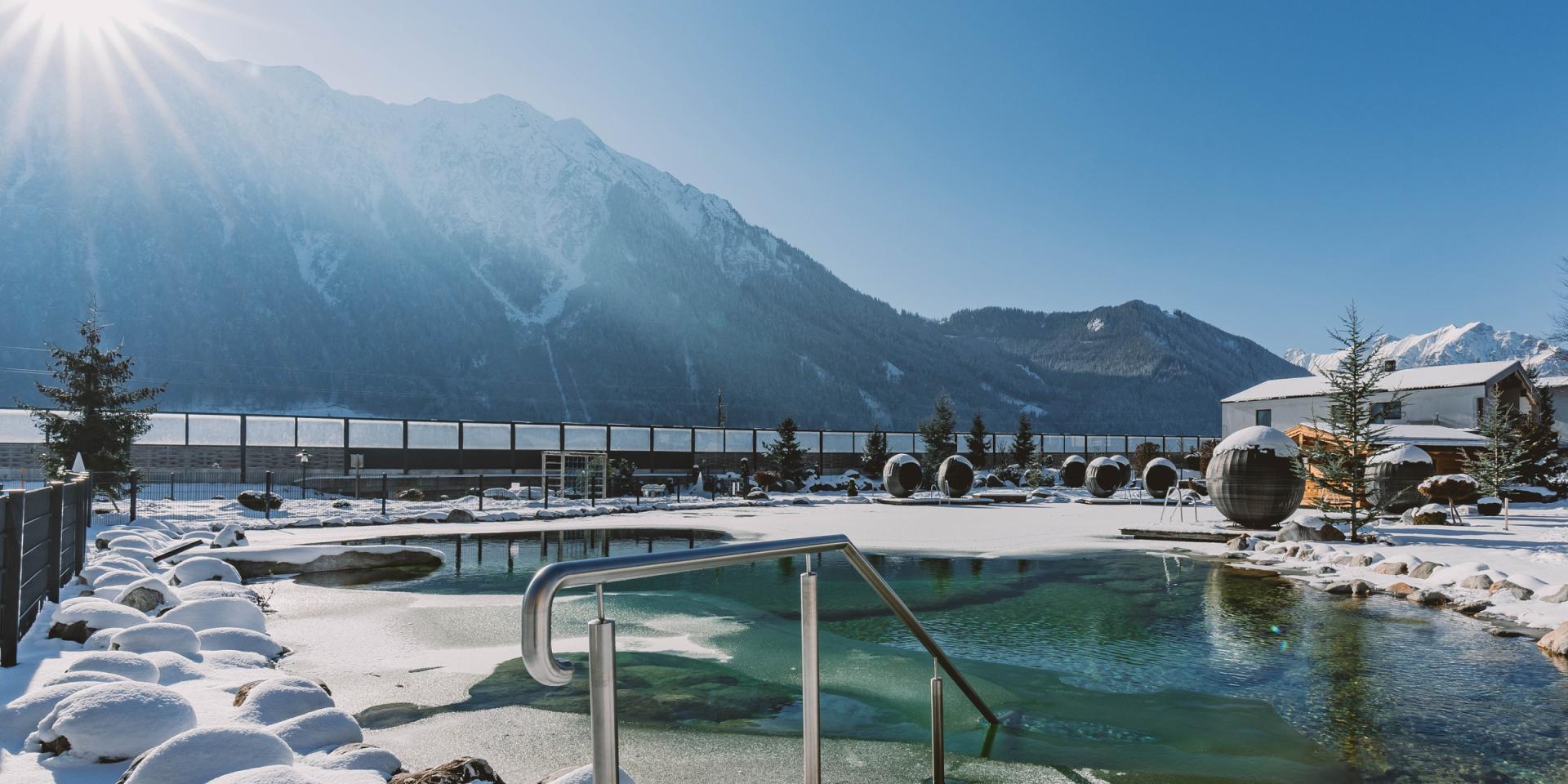 Winterliche Außenpoollandschaft im Familienresort Buchau mit Bergkulisse