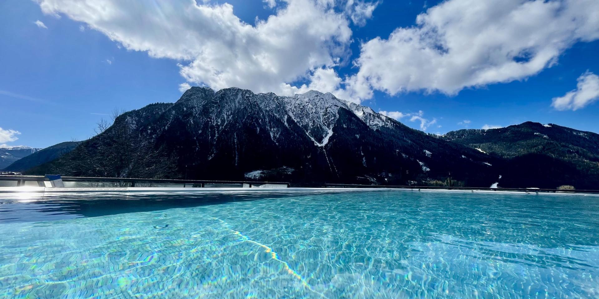 Blick auf den Pool und die Berge im Familienresort Buchau bei klarem Himmel