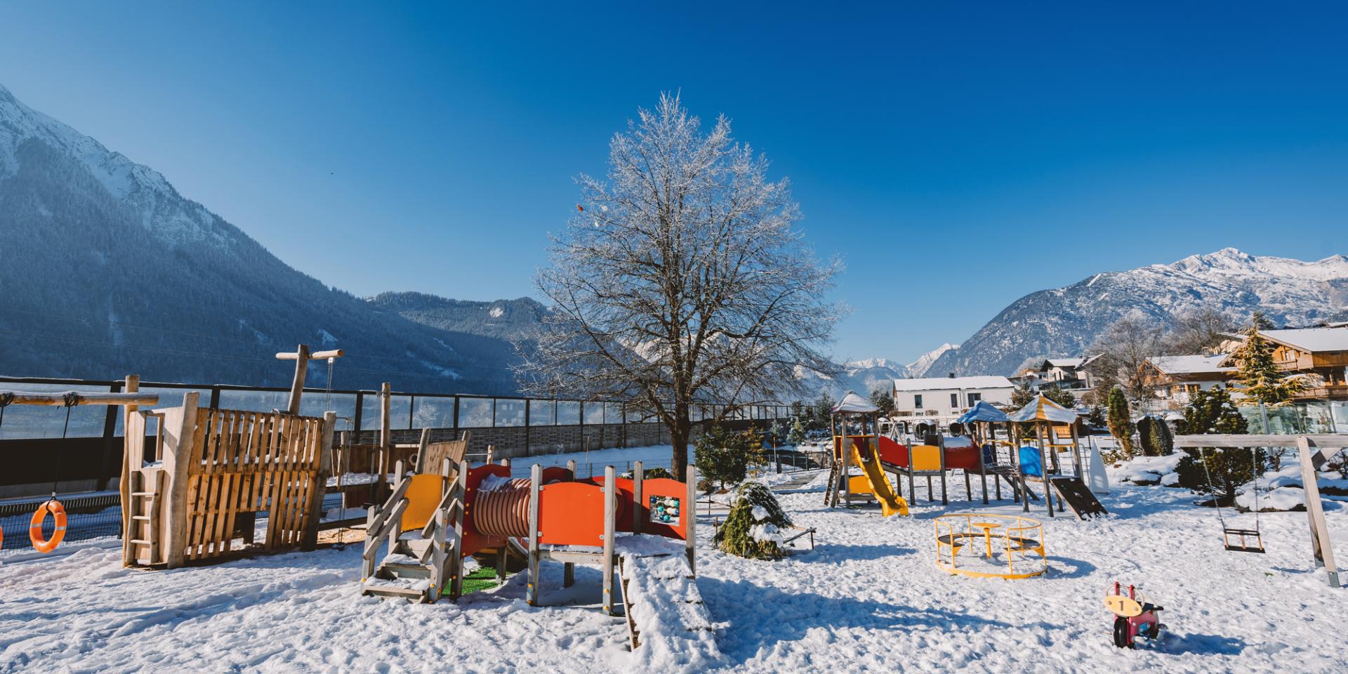 Spielplatz im Familienresort Buchau im Schnee vor Bergkulisse