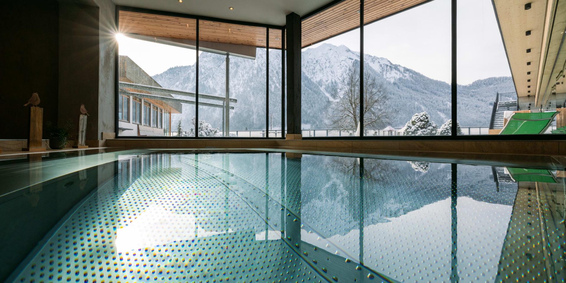 Innenpool im Familienresort Buchau mit Bergblick durch große Fenster