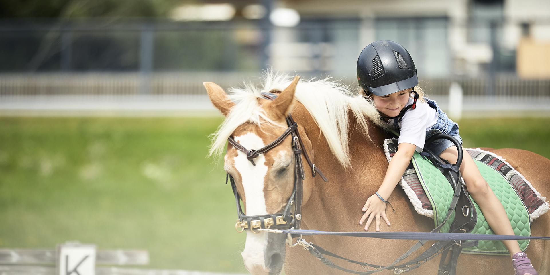 Child hugging and riding horse at Familienresort Buchau