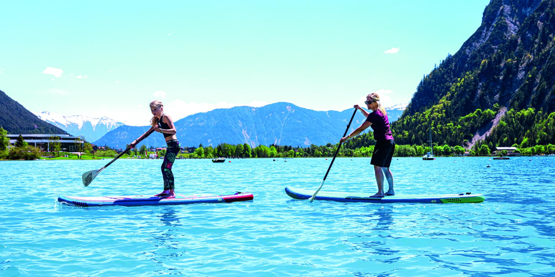 Two people paddleboarding on water at Familienresort Buchau