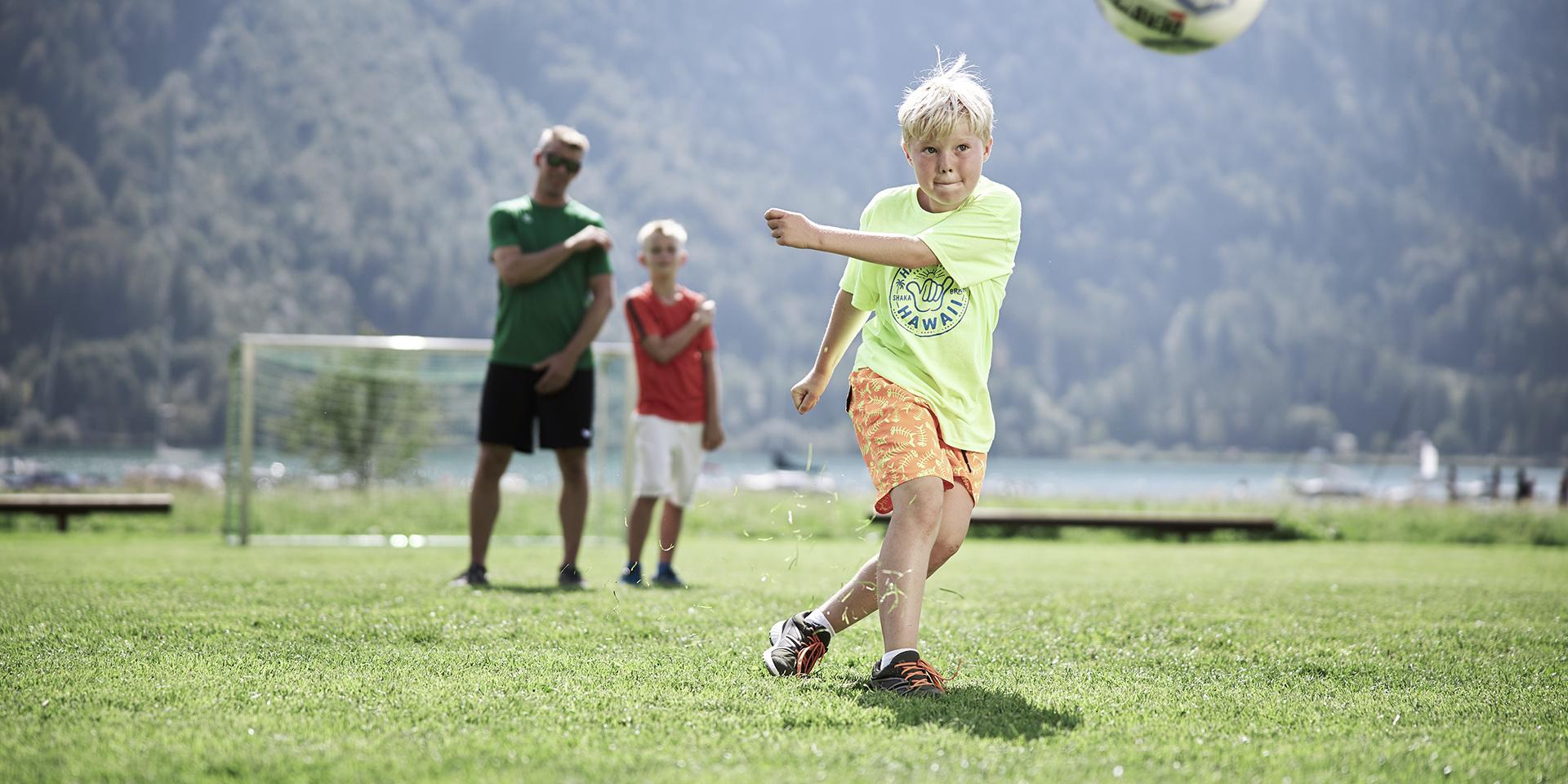 Kind spielt Fußball auf der Wiese im Familienresort Buchau