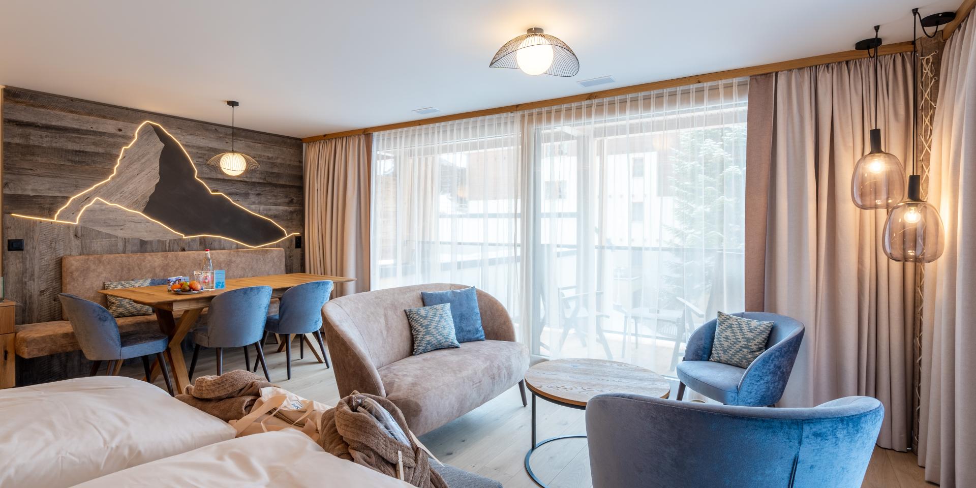 Chambre moderne au Resort La Ginabelle Zermatt avec coin salon et mur de montagne éclairé