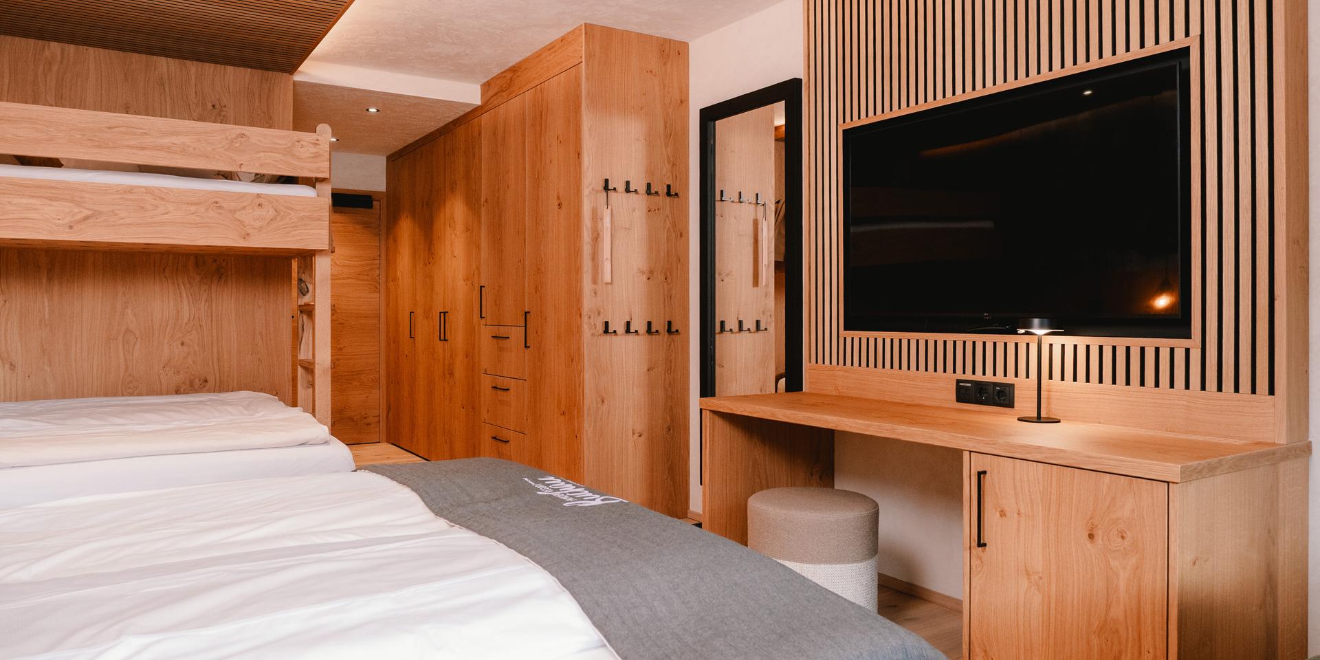 Zimmer im Familienresort Buchau mit Etagenbett, Doppelbett, Holzmöbeln und Fernseher