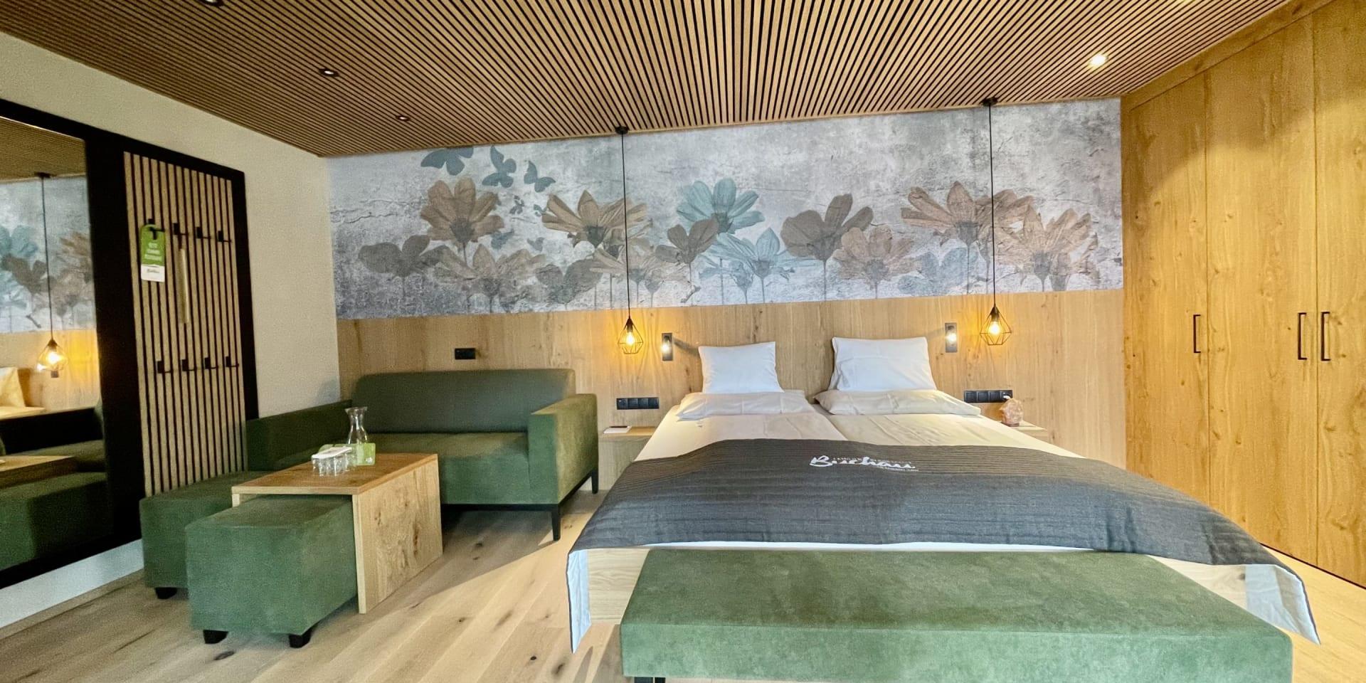 Gemütliches Zimmer im Familienresort Buchau mit Bett, Sofa und Holzmöbeln