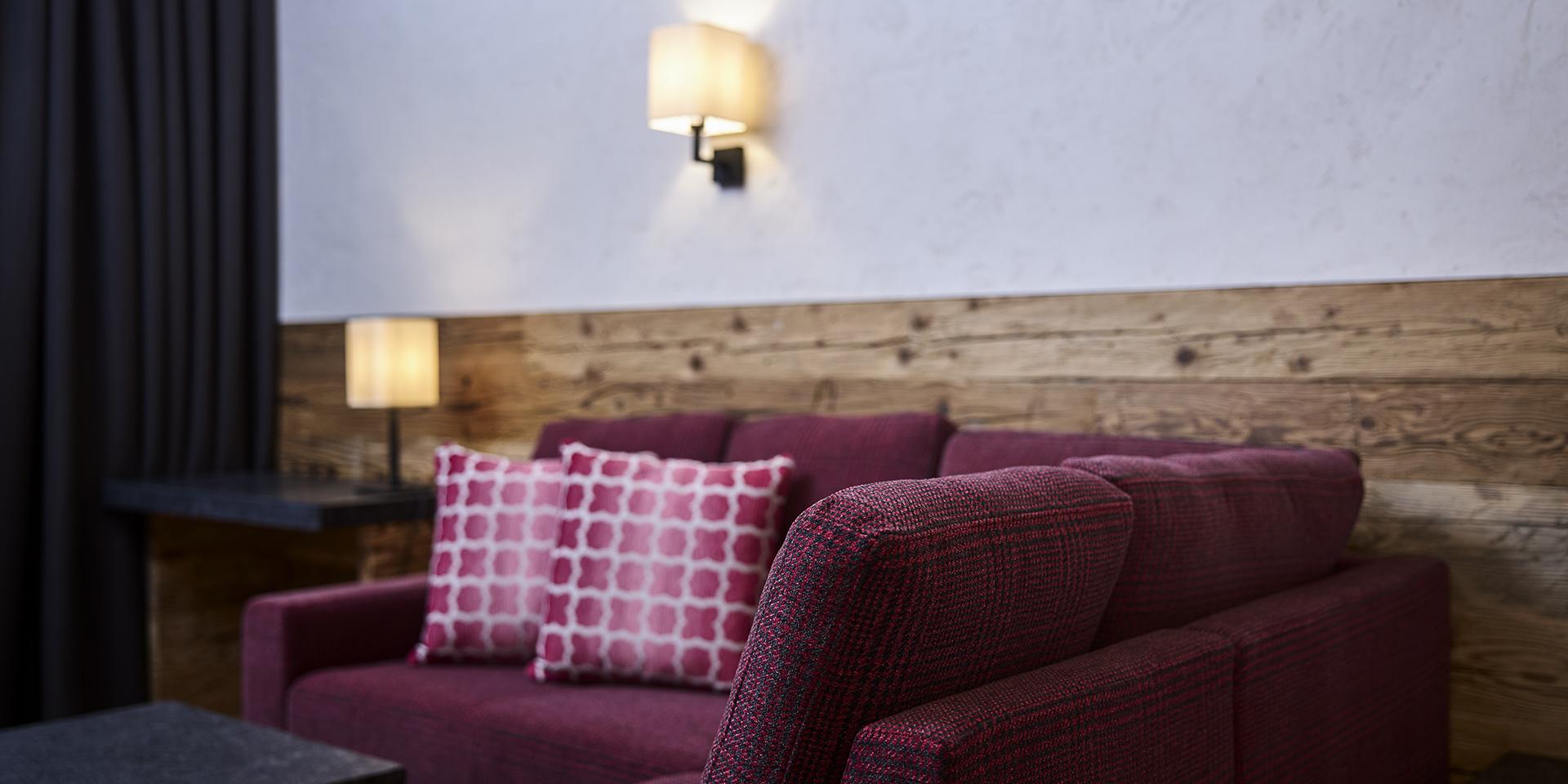 Gemütliche Sitzecke im Familienresort Buchau mit roten Sofas und Holzwand