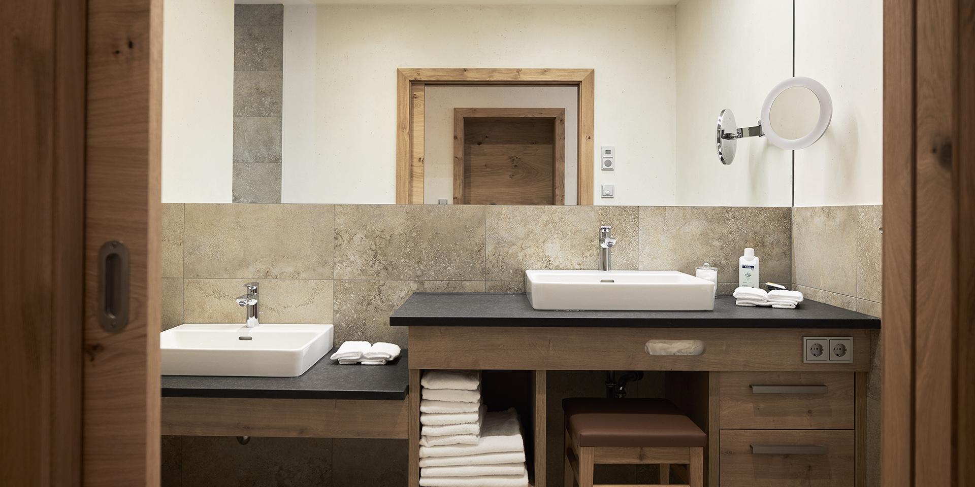 Modernes Badezimmer im Familienresort Buchau mit zwei Waschbecken und Handtüchern