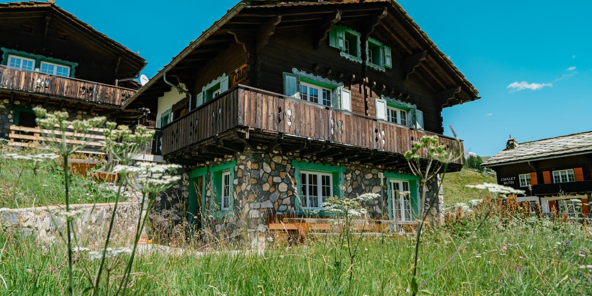 Resort La Ginabelle Zermatt mit traditionellen Chalets und grüner Wiese im Sommer