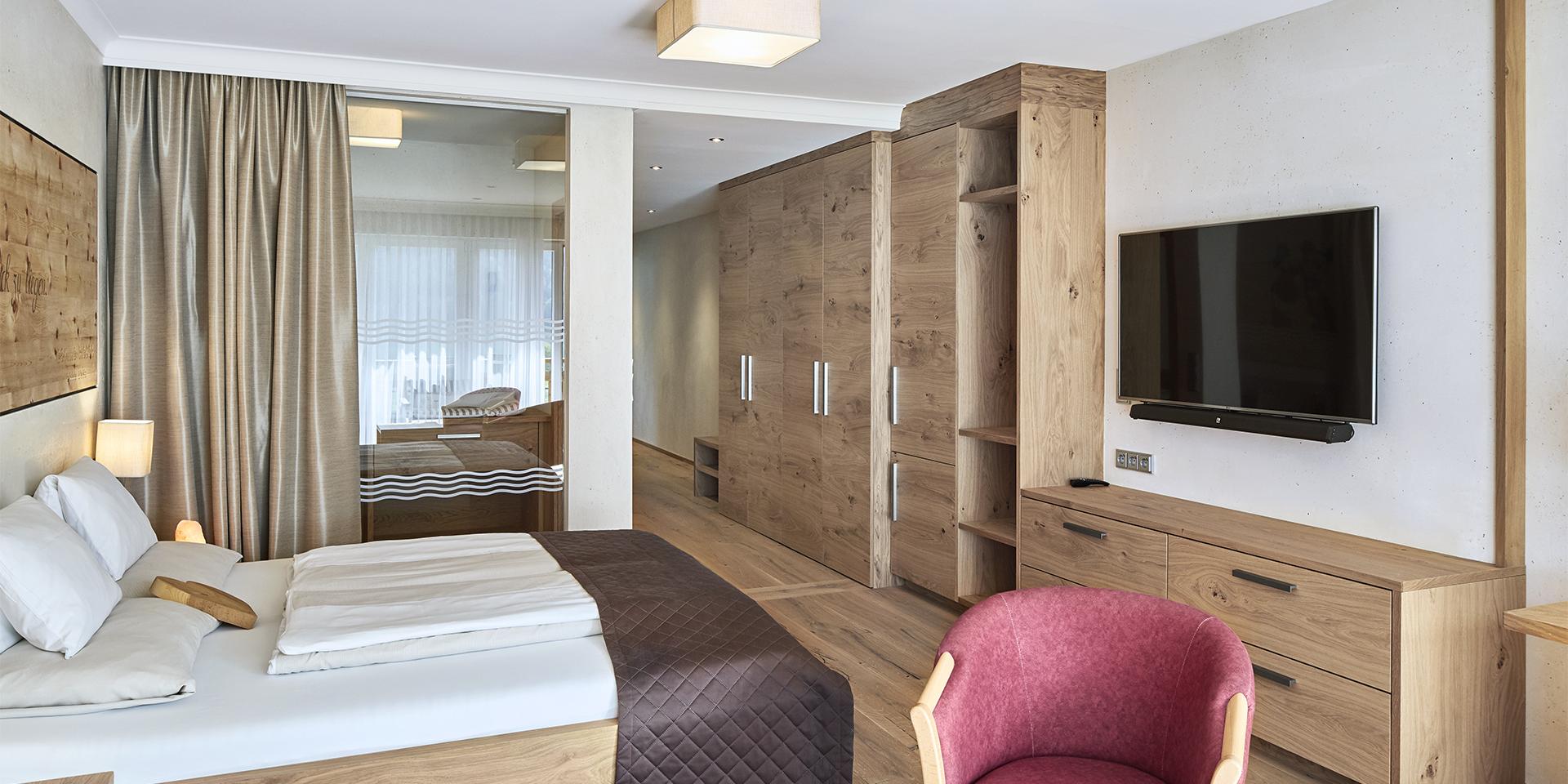 Modern eingerichtetes Zimmer im Familienresort Buchau mit Holzmöbeln und TV