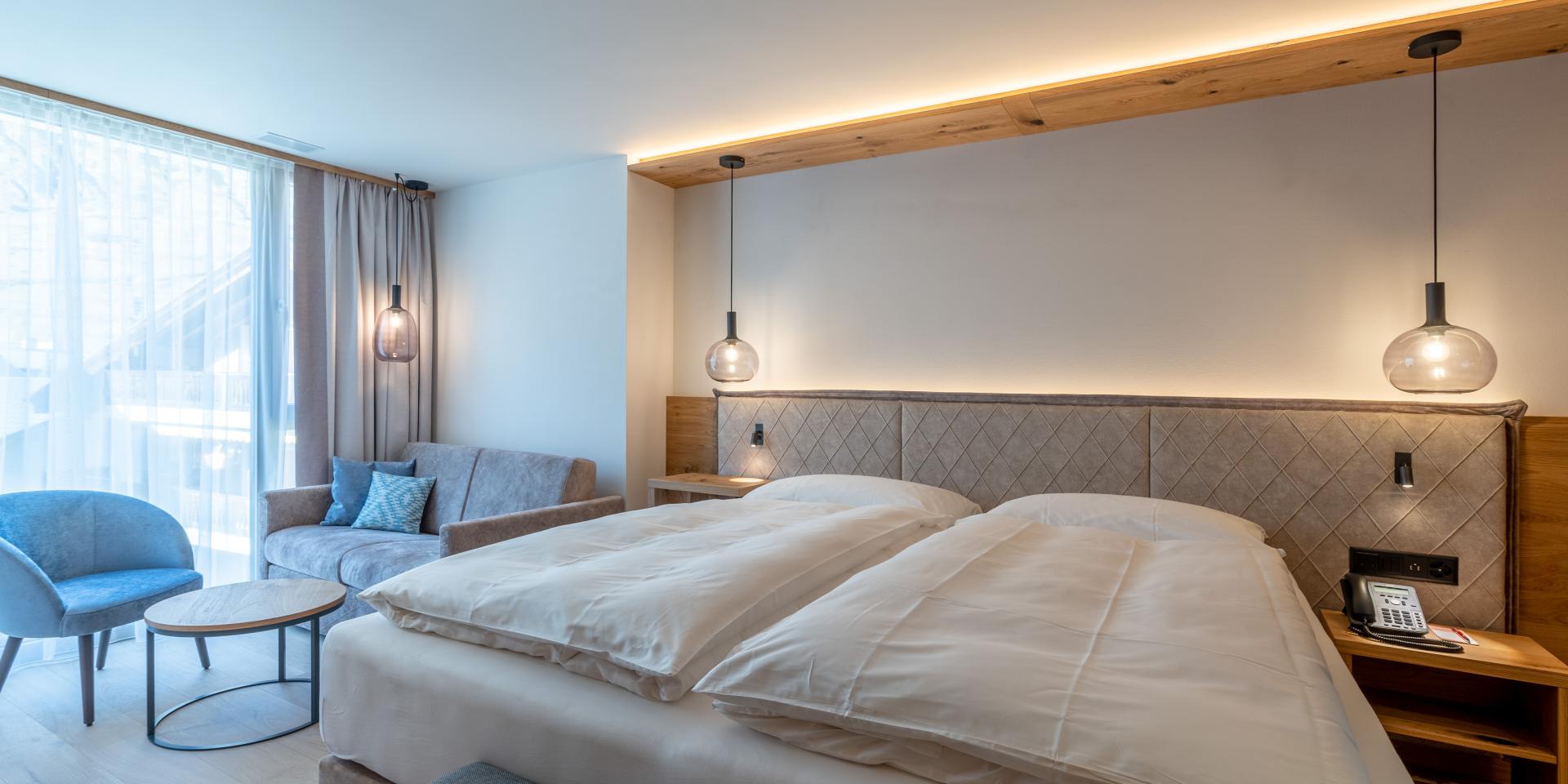Chambre confortable au Resort La Ginabelle Zermatt avec lit double et coin salon