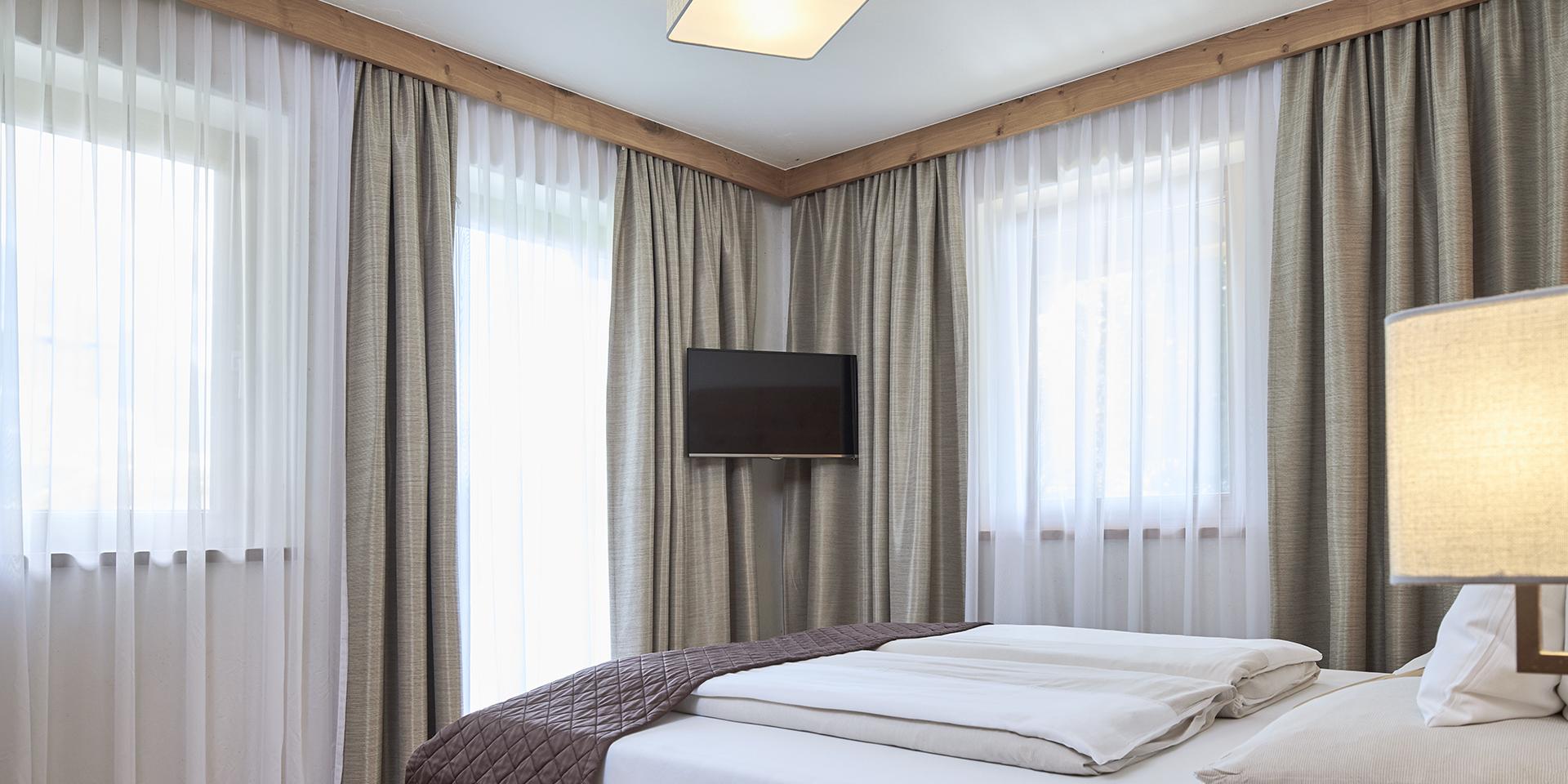 Hell eingerichtetes Schlafzimmer im Familienresort Buchau mit großen Fenstern und modernem Design