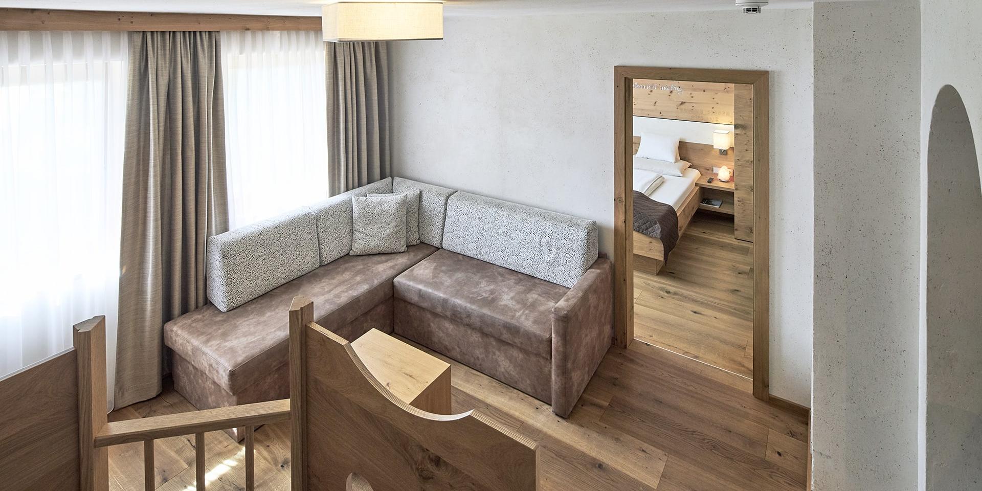 Wohnbereich im Familienresort Buchau mit Sofa und Ausblick ins Schlafzimmer
