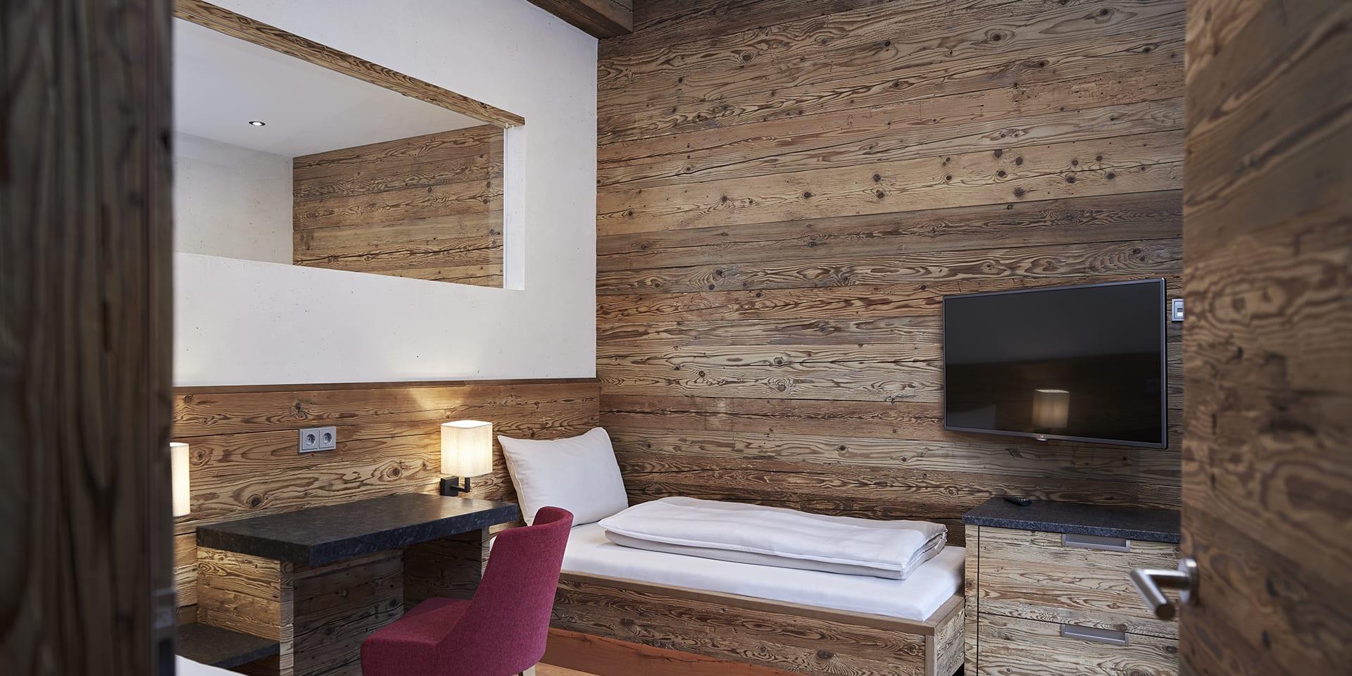 Zimmer mit Holzvertäfelung und Bett im Familienresort Buchau
