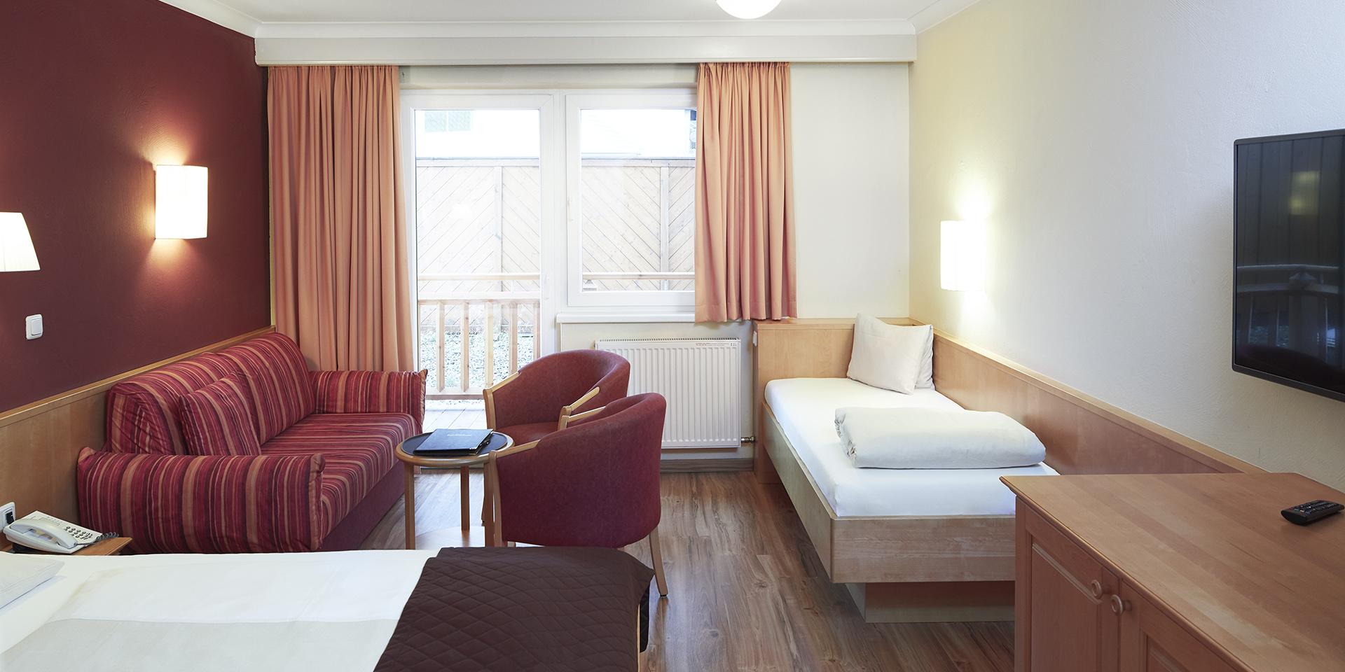 Gemütliches Zimmer im Familienresort Buchau mit Bett, Sofa und Fernseher