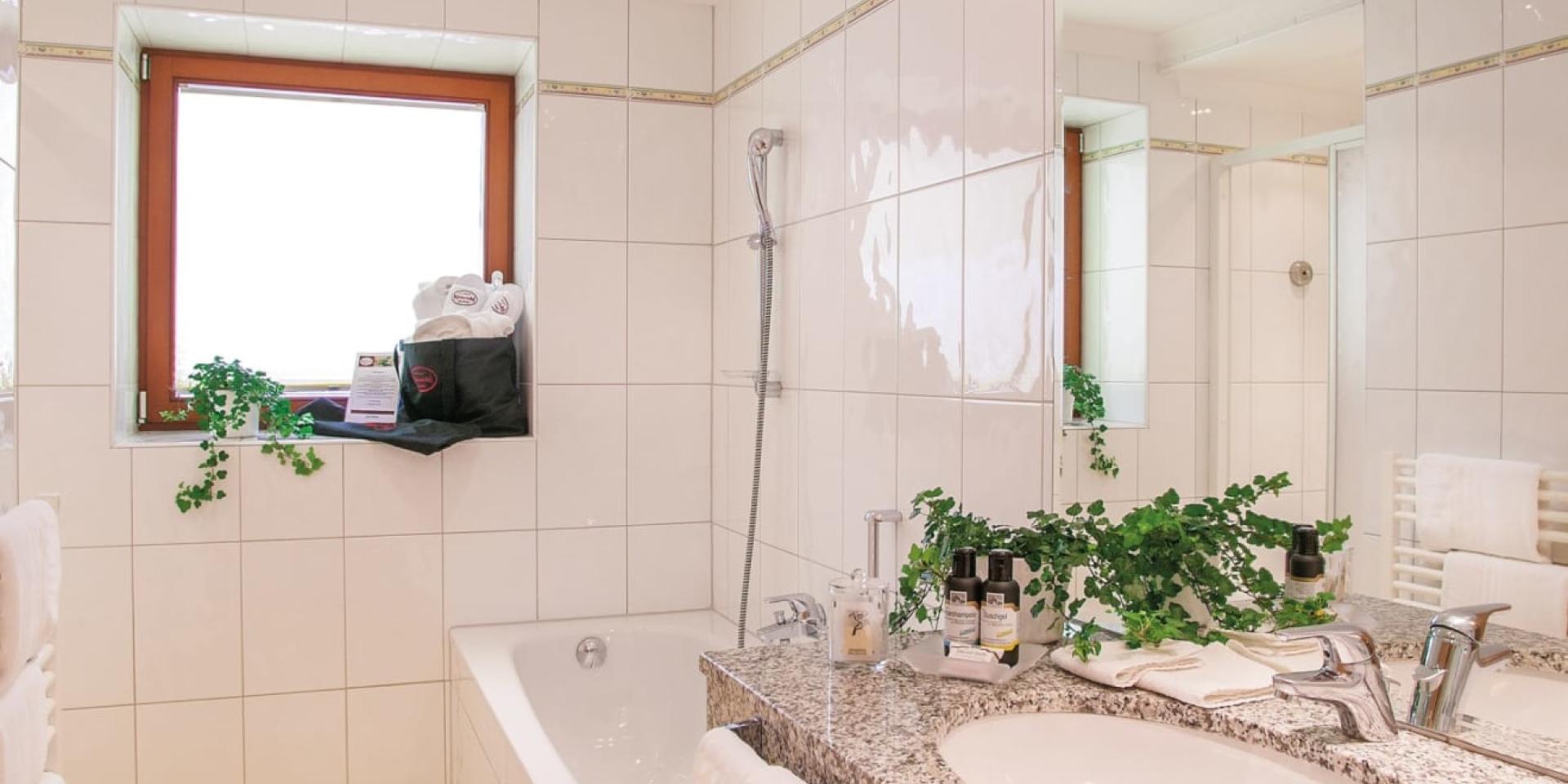 Bright bathroom with bathtub and window at Familienresort Buchau