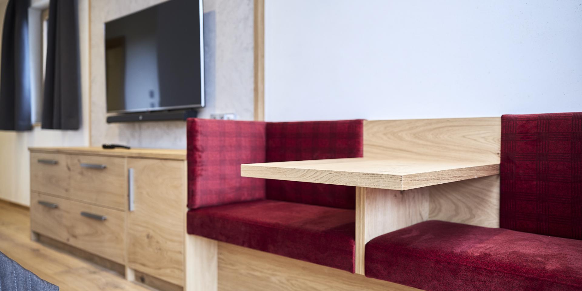 Modernes Wohnzimmer mit Fernseher und rotem Sitzbereich im Familienresort Buchau