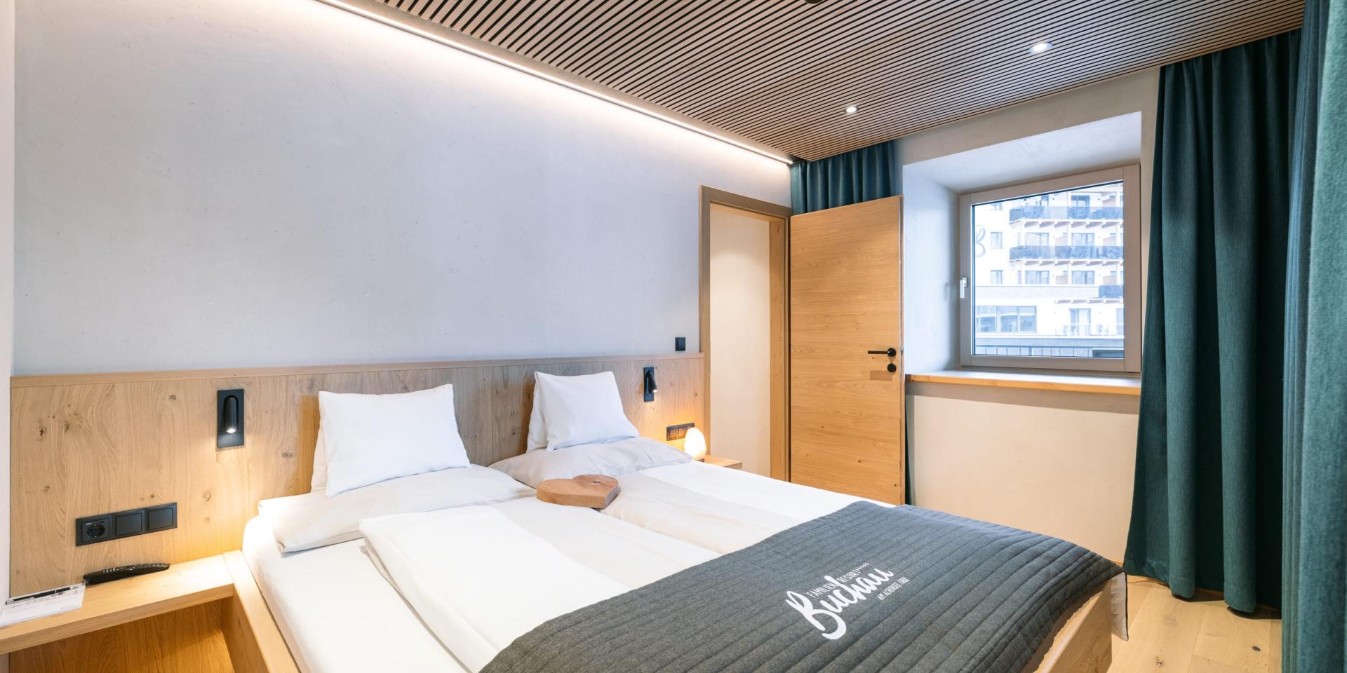 Modernes Doppelzimmer im Familienresort Buchau mit Holzmöbeln und Fenster