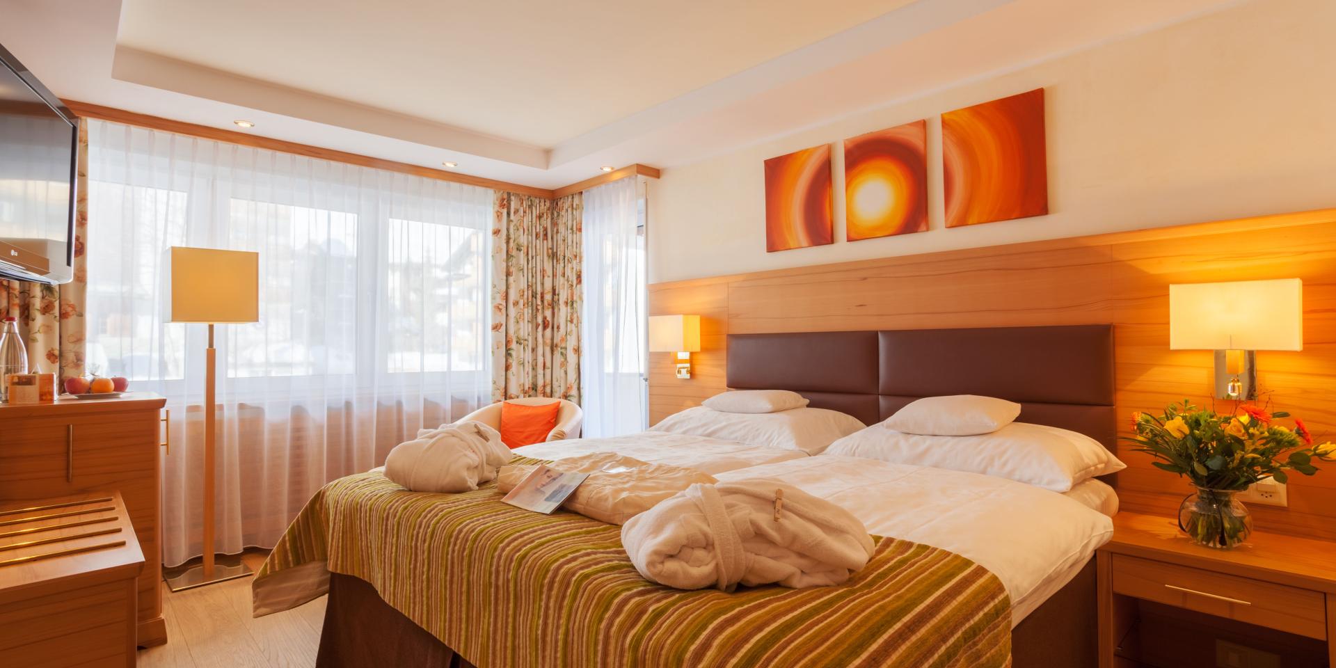 Gemütliches Zimmer im Resort La Ginabelle Zermatt mit Doppelbetten und warmem Licht