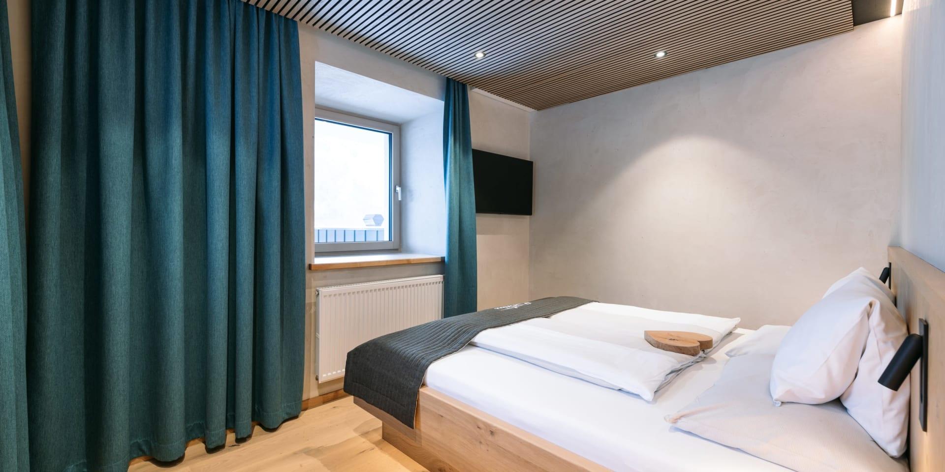 Gemütliches Zimmer im Familienresort Buchau mit Doppelbett und Blick zum Fenster