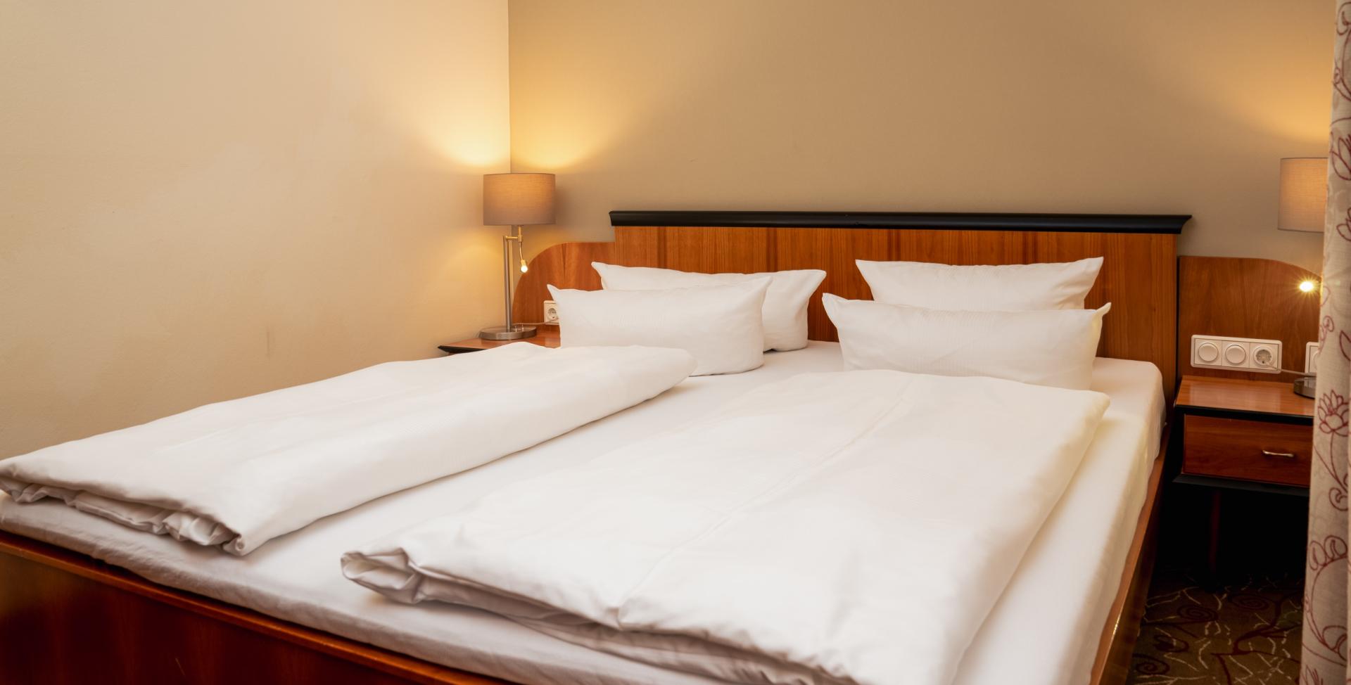 Doppelzimmer im Sport- und Wellnesshotel Angerhof ****S mit Holzbett und weißen Kissen