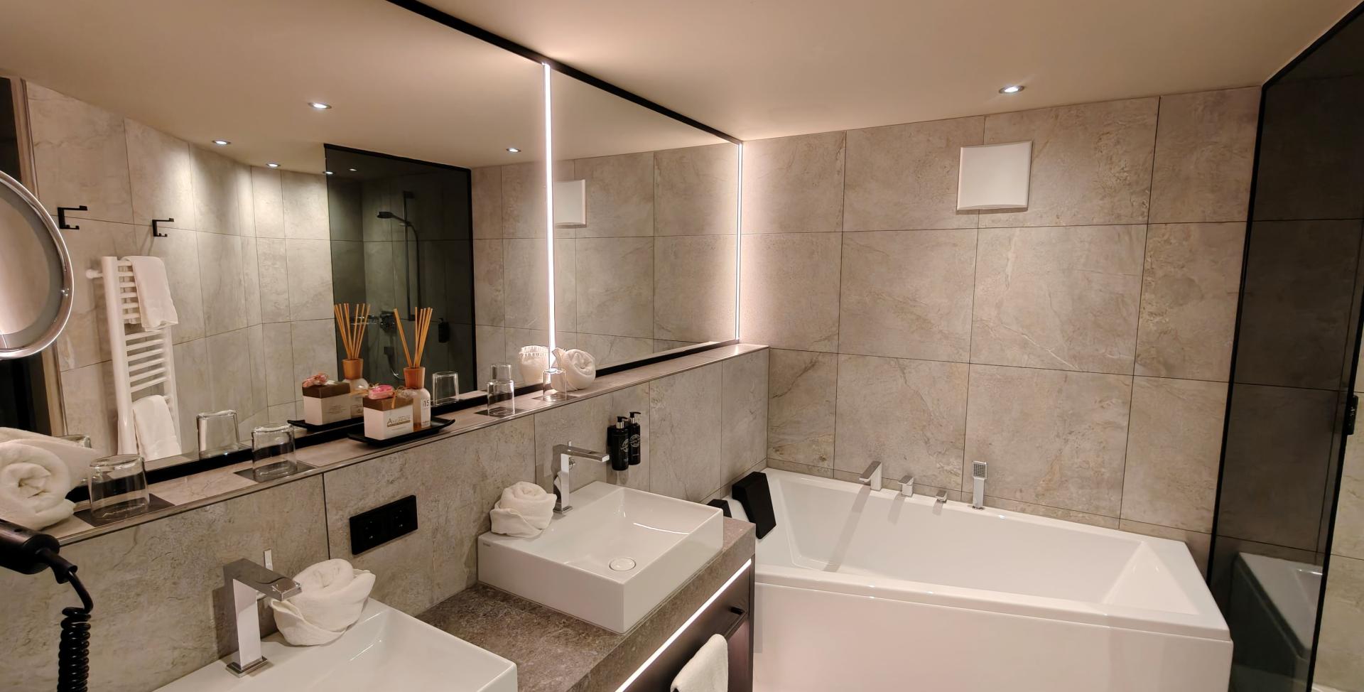 Modernes Badezimmer im Sport- und Wellnesshotel Angerhof ****S mit Badewanne und Doppelwaschbecken.