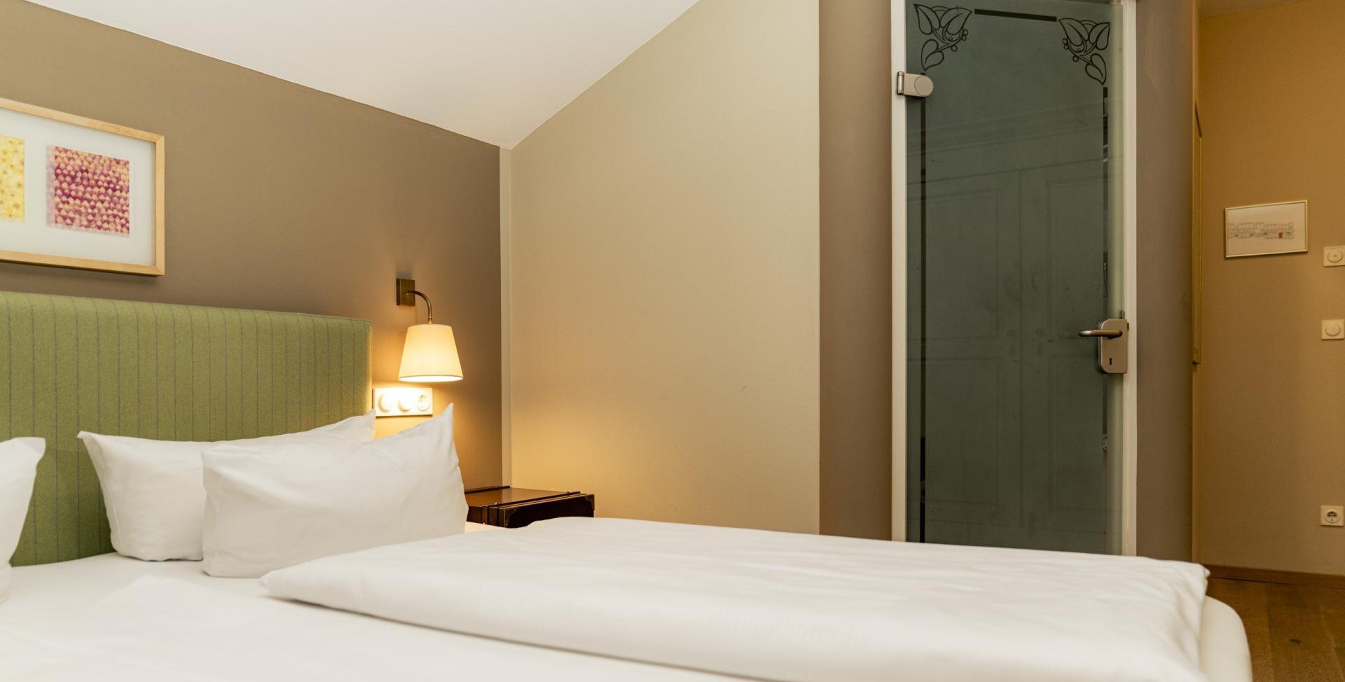 Gemütliches Zimmer im Sport- und Wellnesshotel Angerhof ****S mit grünem Kopfteil und Beleuchtung