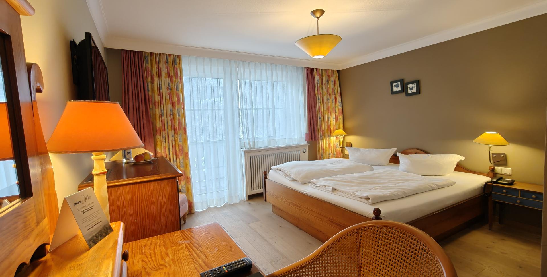 Gemütliches Zimmer im Sport- und Wellnesshotel Angerhof ****S mit Doppelbett und Holzmöbeln