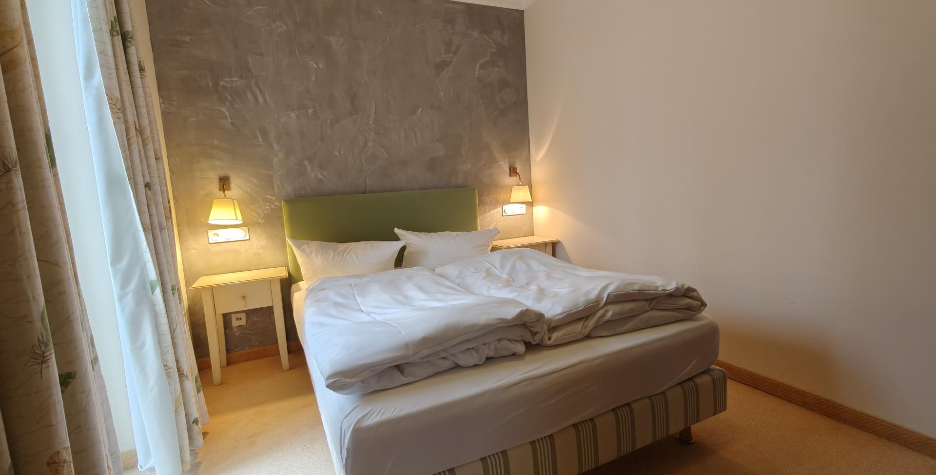 Modernes Doppelzimmer im Sport- und Wellnesshotel Angerhof ****S mit grüner Wand und Fenster