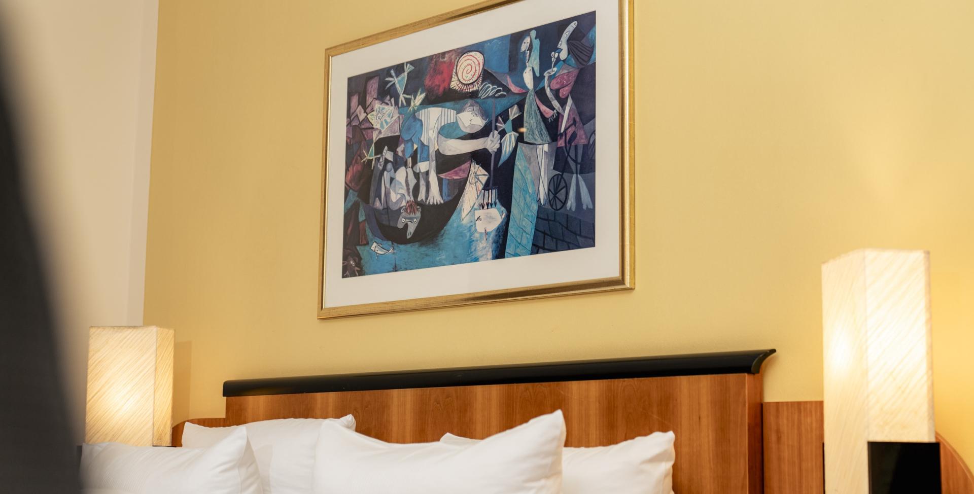 Wohnliches Zimmer mit Kunst über dem Bett im Sport- und Wellnesshotel Angerhof ****S