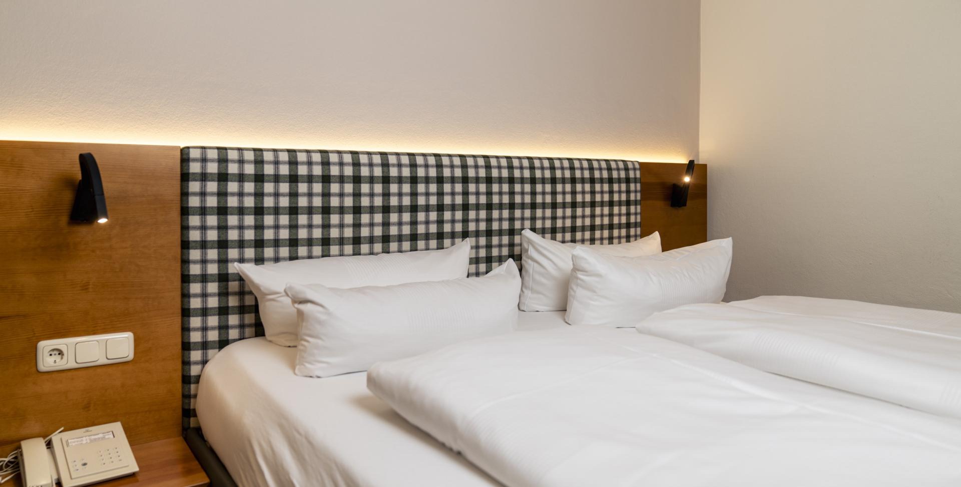 Gemütliches Bett mit kariertem Kopfteil im Sport- und Wellnesshotel Angerhof ****S